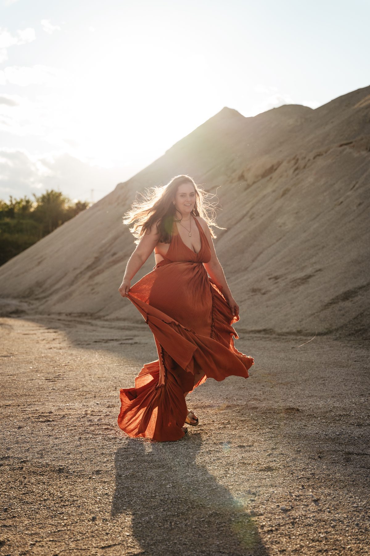 Virginia dancing freely in a flowing red dress at sunset